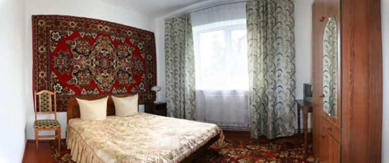 Cozy bedroom with patterned rug and large window viewpoint